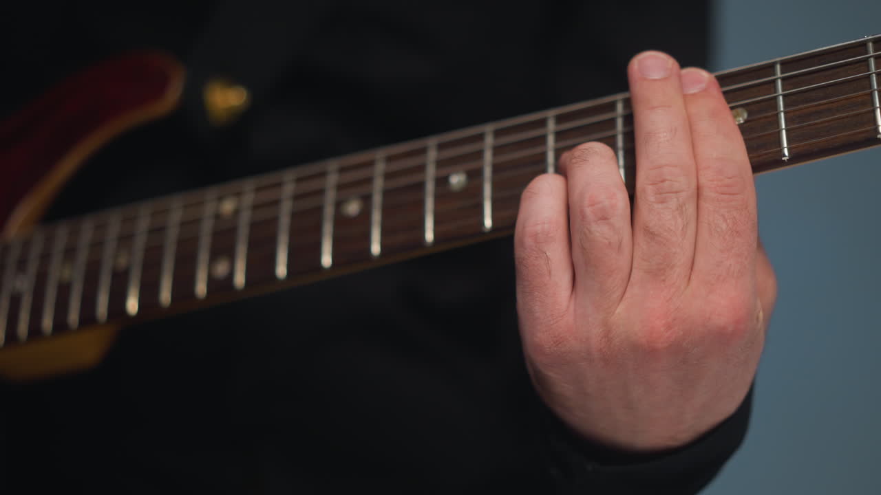 vista cercana del dedo de un guitarrista tocando una cuerda de guitarra, destacando la precisión y la técnica de la mano del músico. la toma detallada captura las complejidades de las cuerdas de la guitarra