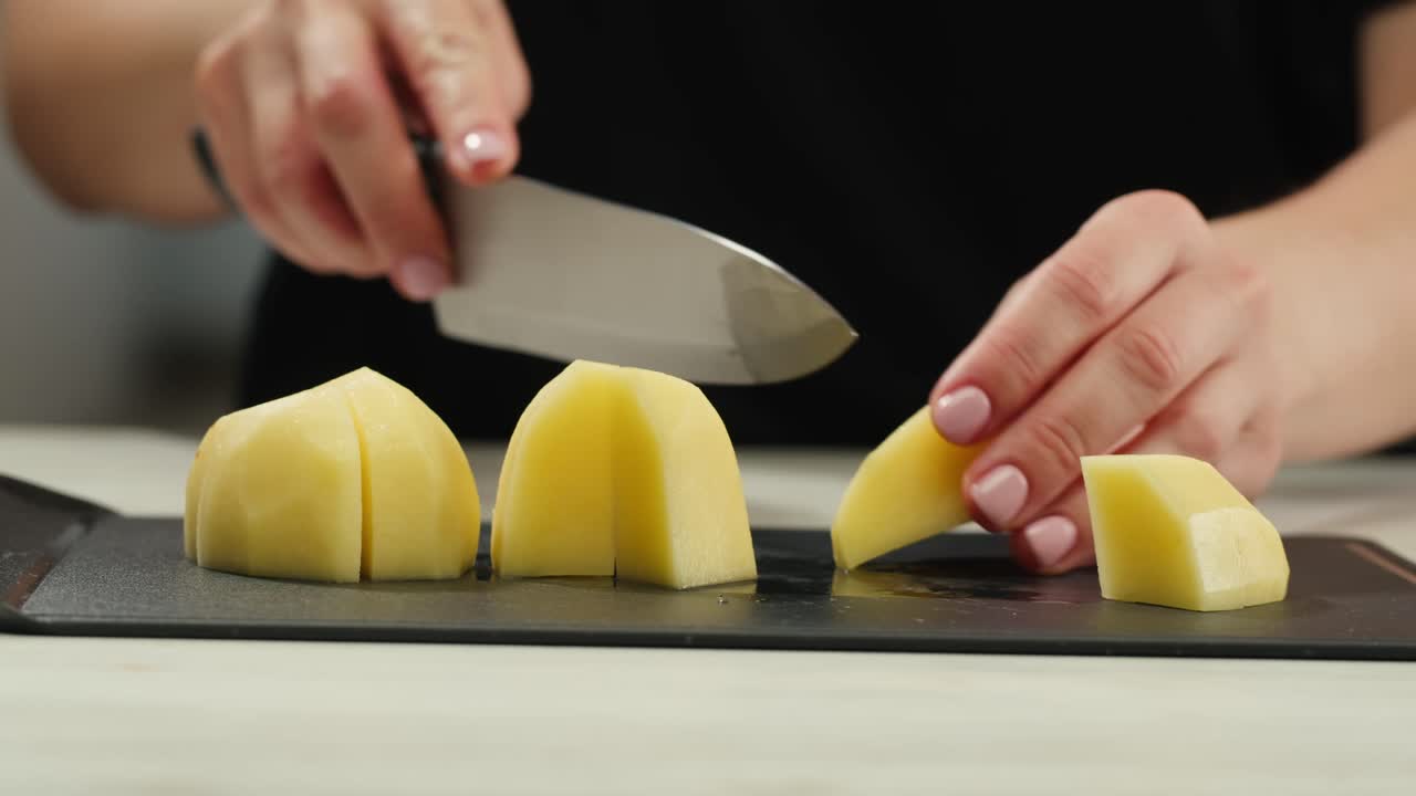 Woman cutting potato on table in kitchen. High quality 4k footage
