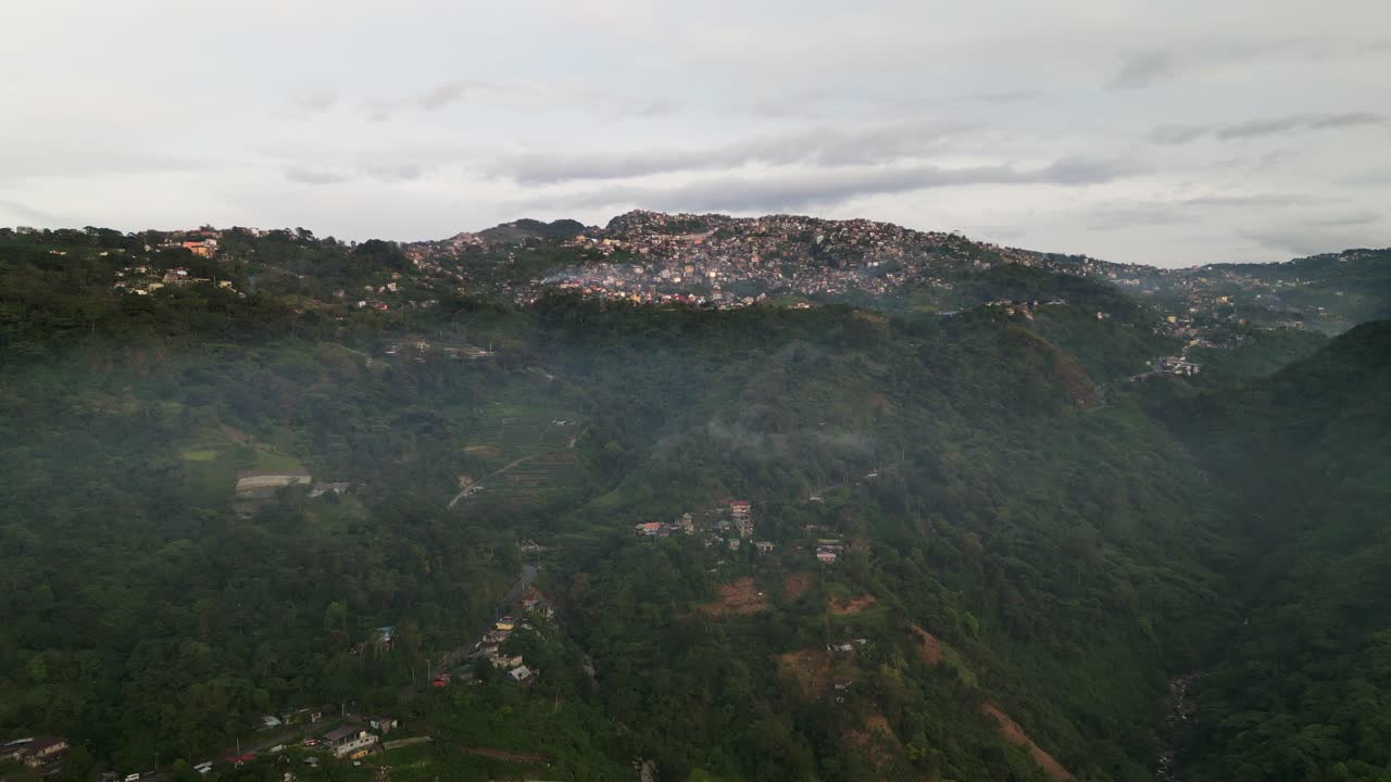 Vista aerea panoramica di Tuba, provincia di Benguet, Filippine, con insediamenti montani d'alta quota lungo pendii boscosi sotto cieli nuvolosi