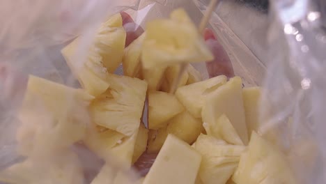 girl-hand-holds-plastic-bag-with-pineapple-slices-closeup