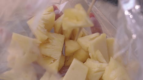 la mano de la niña sostiene una bolsa de plástico con rodajas de piña en primer plano
