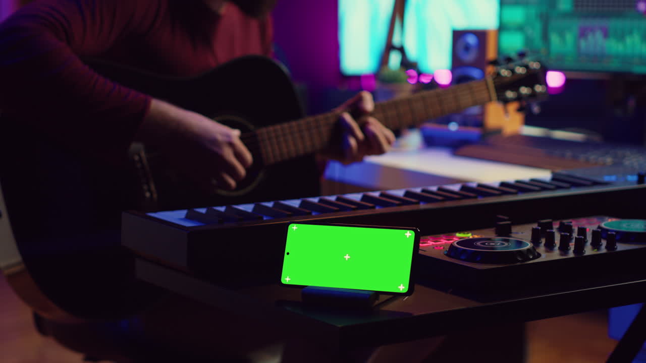 compositor tocando guitarra acústica en un estudio casero con pantalla verde