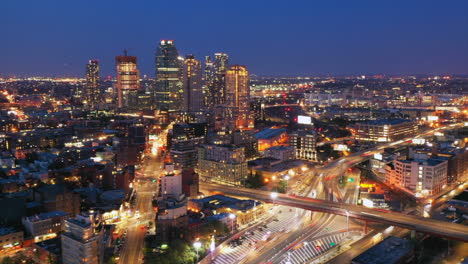 an aerial cinematic dusk to night, time lapse by a busy highway in brooklyn new york with cars, trains - planes in motion