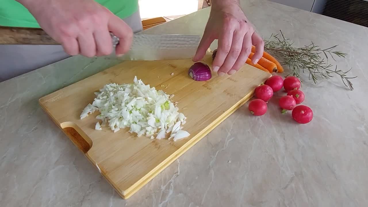 cortar cebollas rojas en una placa de corte de bambú con el cuchillo japonés ryukiri nakiri