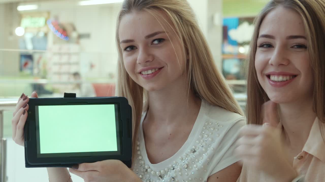 Two Girls Show The Tablet With The Green Screen