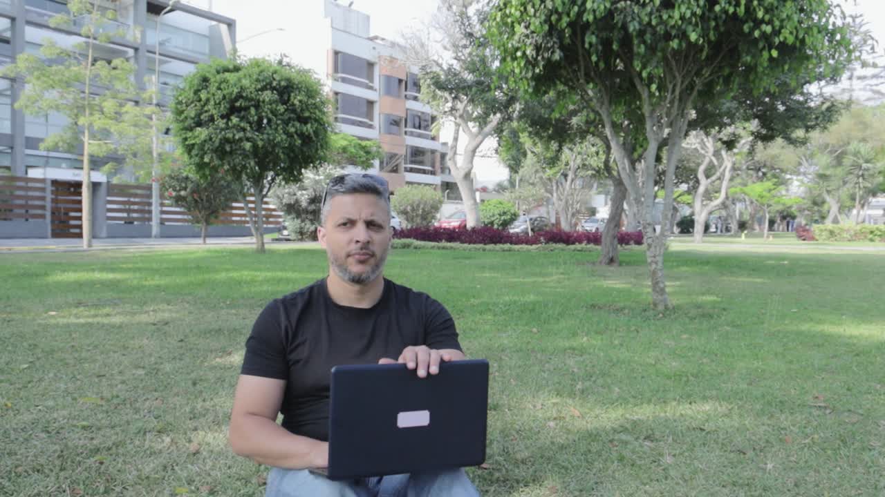 Hombre trabajando a distancia con un portátil en un parque
