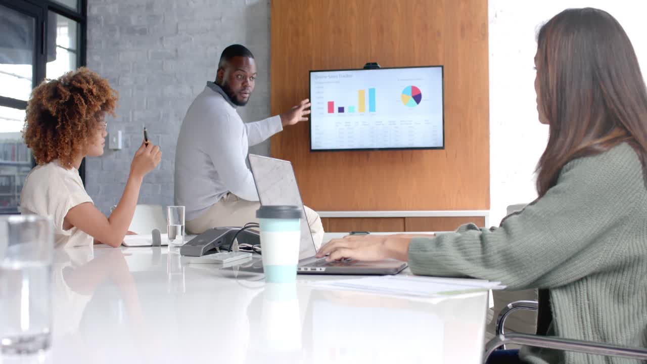 Diverse male and female colleagues using laptop and monitor at office meeting, slow motion