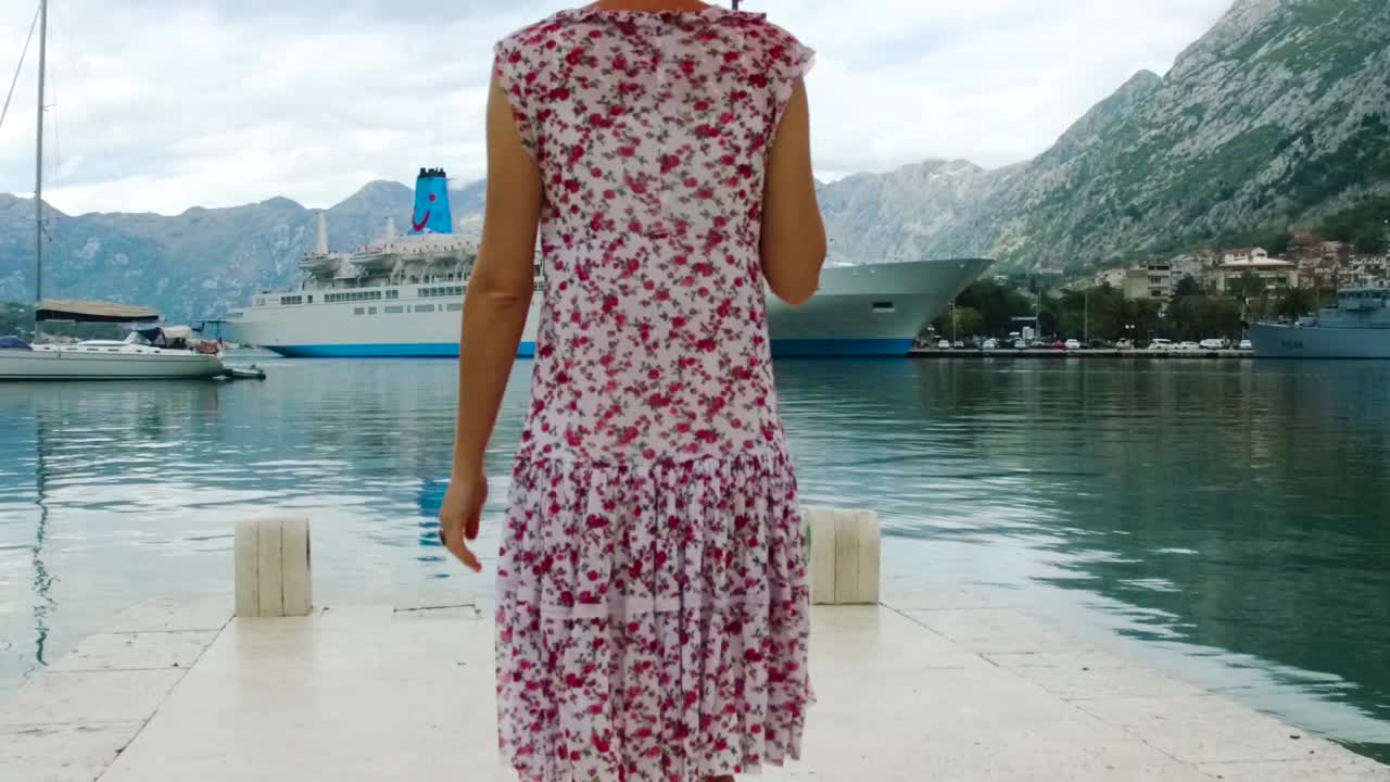 mujer caminando en un muelle con una vista de un crucero