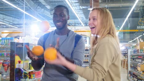 couple juggling oranges in a grocery store