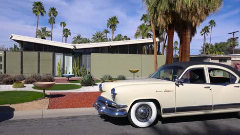 exterior establishing shot of a palm springs california mid century modern home with classic retro cars parked outside