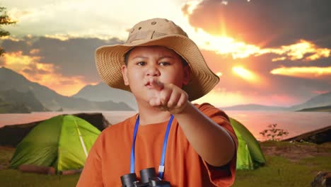 boy pointing at a sunset during camping trip
