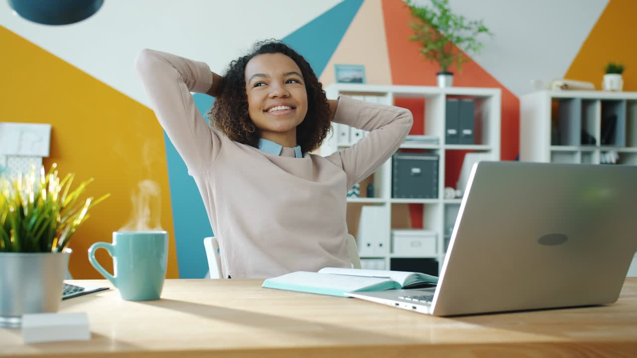 bucle de cinemagraph de chica de raza mixta relajándose en la oficina mientras el vapor se eleva de la taza de café caliente