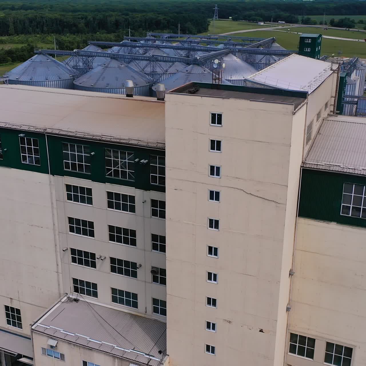 Abundant neat territory of agricultural plant for processing crops. Modern premises, trains and silo tanks at the nature backdrop