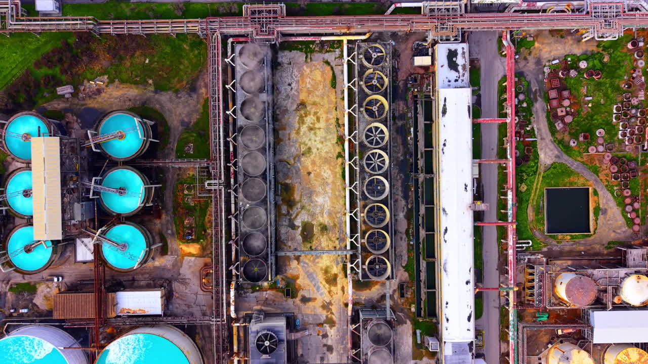 Circular turquoise water basins and cooling systems at an industrial site. Top down aerial view of industrial water treatment tanks
