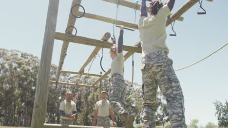 Diverse-male-and-female-soldier-hanging-on-trapeze-bars-at-army-obstacle-course-in-the-sun