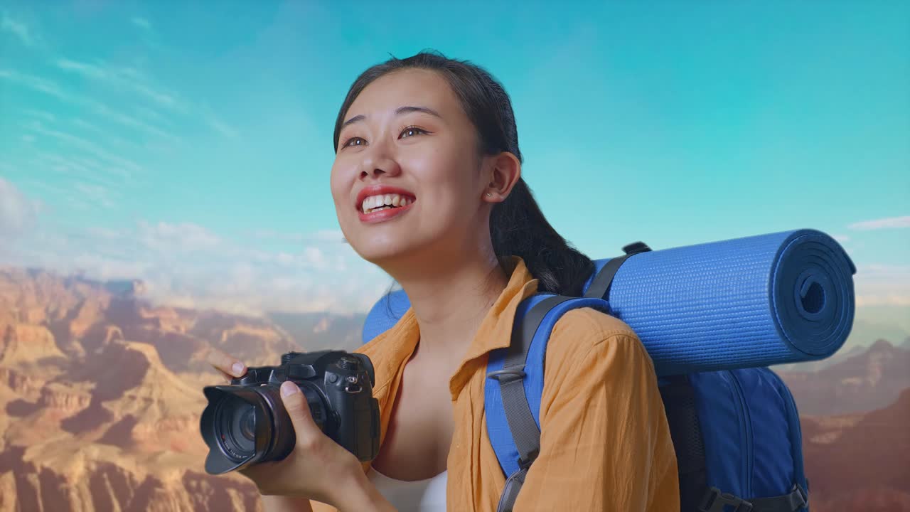Close Up Side View Of Asian Female Hiker With Mountaineering Backpack Smiling And Holding A Camera In Her Hands Then Looking Around While Traveling At The Top Of Mountain
