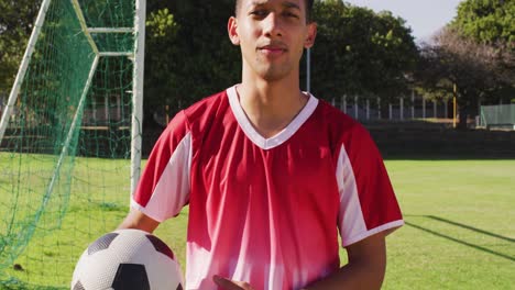 video of diverse male biracial football player standing on field with ball