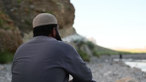 a tensed pakistani man in white cap smoking cigareete in a flood affected area in balochistan