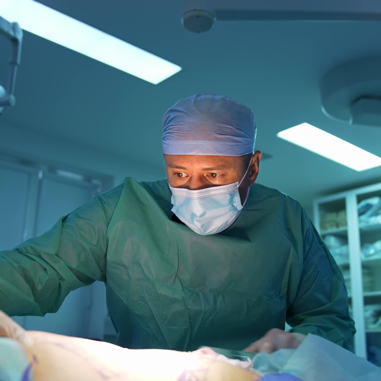Portrait of a doctor doing liposuction procedure. Surgeon pumping fat from patient's abdomen on operating room background