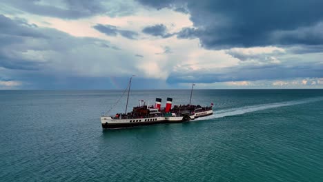 a breathtaking aerial view captures a graceful paddle steamer gliding serenely across calm seas, its vintage charm highlighted by the slow, sweeping motion of the camera