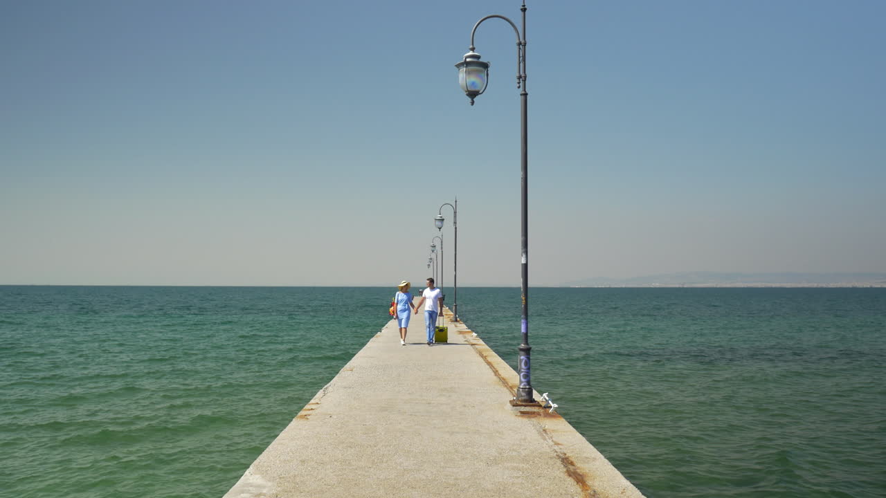 una pareja joven con una maleta en el muelle.