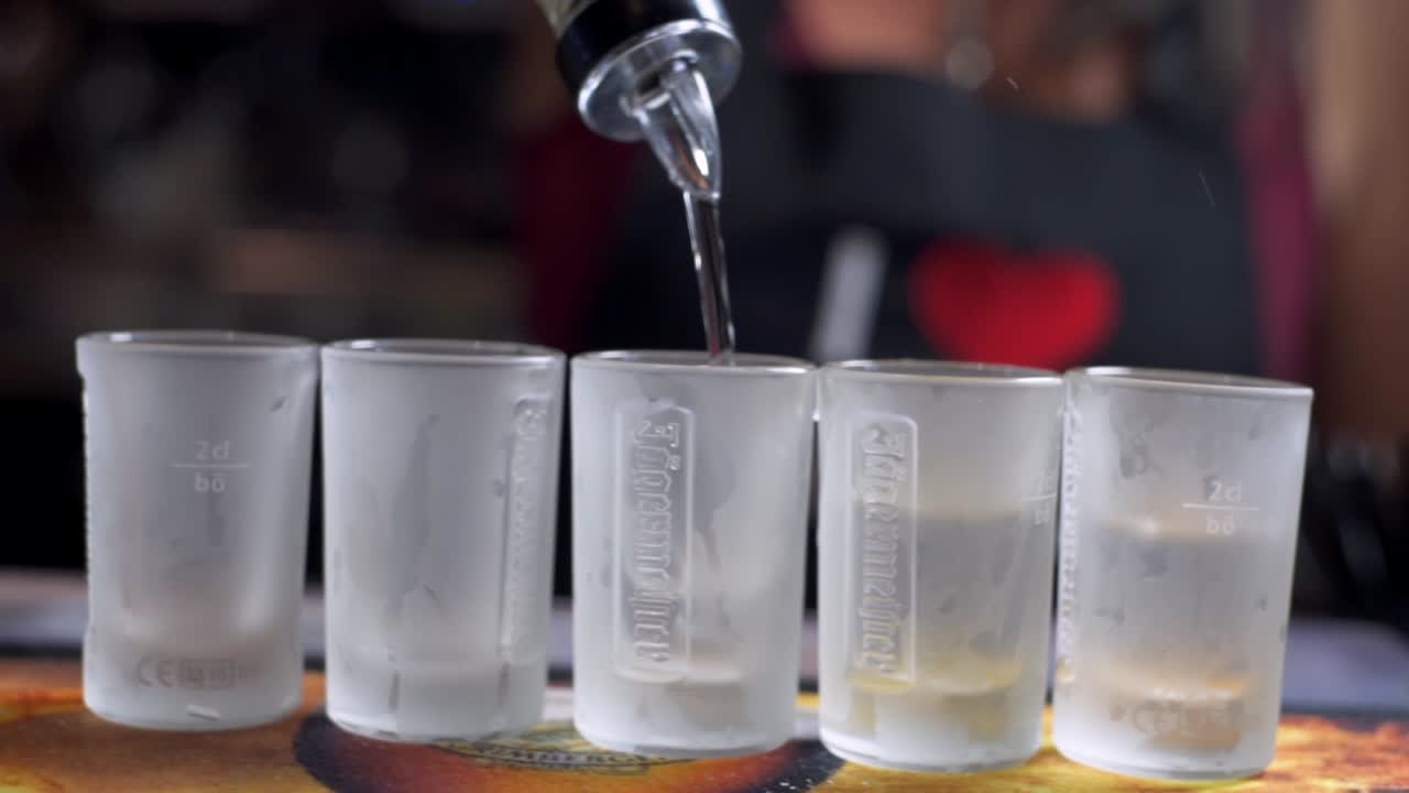 Woman serving drink shots tequila in a bar