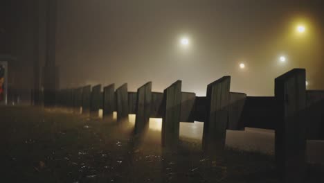 Holzbarriere-An-Der-Seitenstraße-Mit-Leichtem-Schatten-Fahrender-Autos-In-Der-Nacht