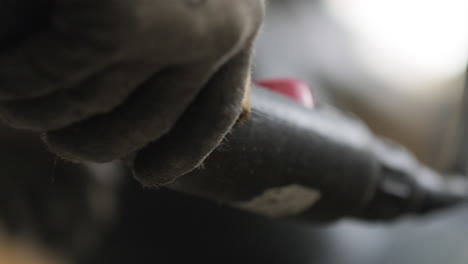 primer plano de un trabajador que opera una grúa elevadora con controlador, guantes que cubren las manos