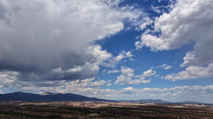 Timelapse 4K con dron de un clima cambiante y densas nubes monzónicas. Un sistema meteorológico masivo se desplaza por un cielo amplio, proyectando sombras dinámicas sobre un vasto paisaje de mesetas en el desierto alto.