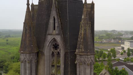 Saint-Michael's-Church-in-Ballinasloe-Galway-push-in-and-orbit-around-lichen-covered-gothic-towers