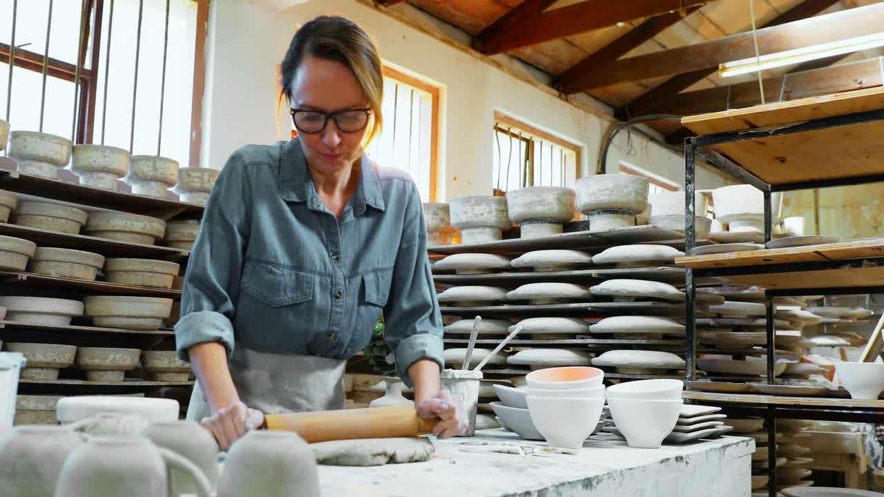 una mujer alfarera aplanando el barro con un rodillo 4k