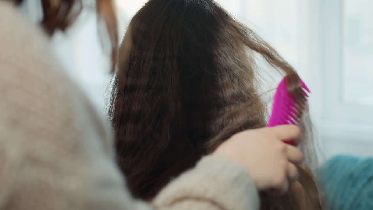 Person Carefully Styles Flowing Hair, Individual Styling Long Wavy Hair With Gentle Combing Techniques, Detailed View Of Person Meticulously Arranging Flowing Locks Using Comb Near Natural Daylight