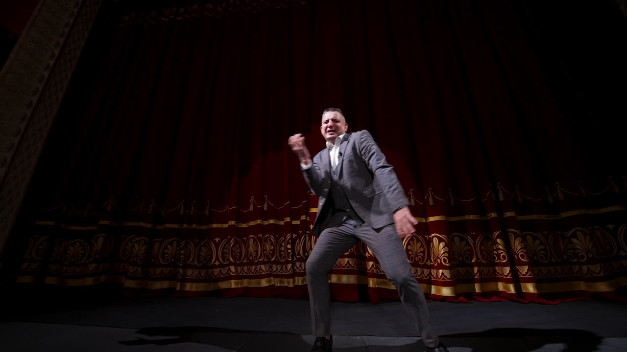 Middle age male entertainer, presenter or actor on stage. Public speaker gives performance. Man in theater.