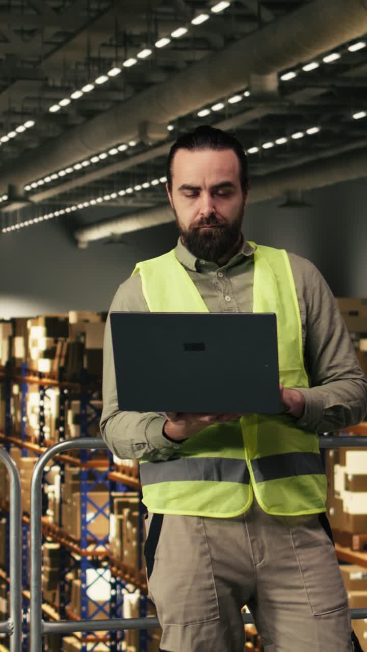 Video verticale: ritratto di dipendente uomo che controlla i dettagli della spedizione con un laptop su una piattaforma.