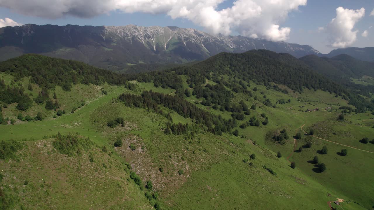 paisaje alpino verdoso con las montañas piatra craiului como telón de fondo, día soleado, vista aérea
