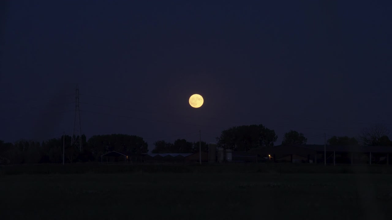 Bulan Stroberi dalam pemandangan malam yang tenang, menampilkan bulan purnama terbit di atas lanskap pedesaan dengan pepohonan dan bangunan berbayangan yang terlihat, gerakan dinamis, dan pencahayaan atmosfer.