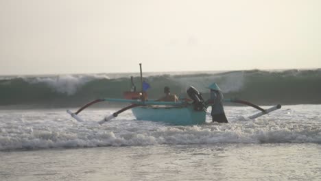 pushing a fishing canoe into the waves