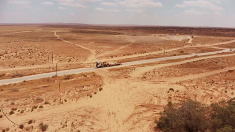 vista aérea de la carretera vacía en el desierto mientras un gran camión conduce por la carretera