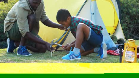 Father-teaching-son-to-use-a-hammer-for-setting-up-a-tent