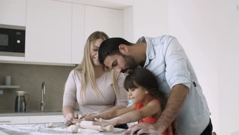 young parents and their girl rolling dough