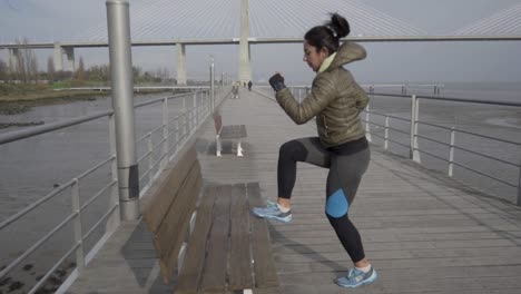 Slow-motion-shot-of-focused-young-woman-training-on-pier-at-seaside