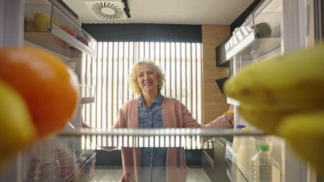woman looking inside a refrigerator filled with fresh fruit
