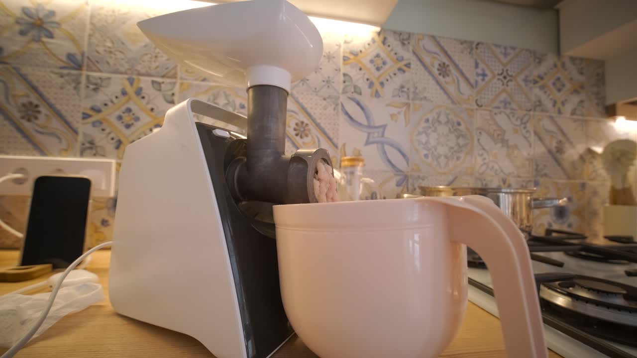 Electric Meat Grinder Processing Raw Meat in a Home Kitchen