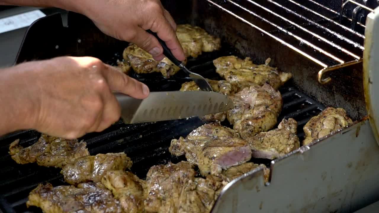 Cooking chicken on a bbq, cutting chicken pieces into smaller portions