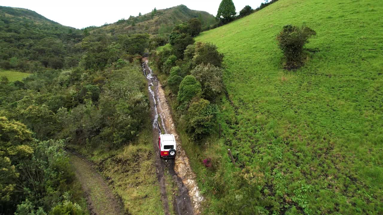 콜롬비아 쿤디나마르카에서 시골길을 건너는 지프차를 따라 공중 촬영