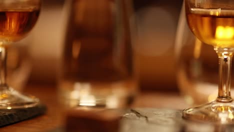 a detailed view of whiskey glasses filled with amber liquid on a wooden table.