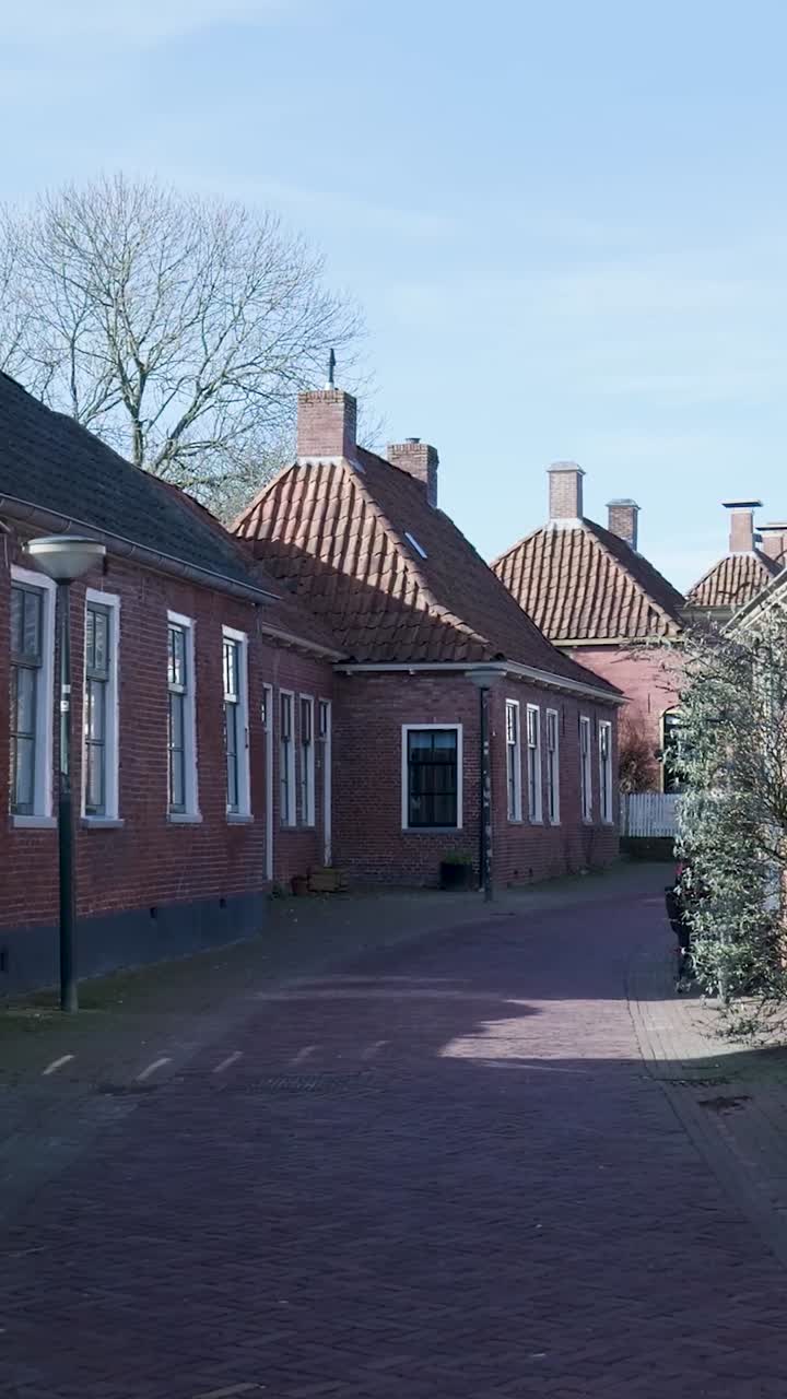 Stille historisk murstensgade flankeret af gamle huse på en solrig dag