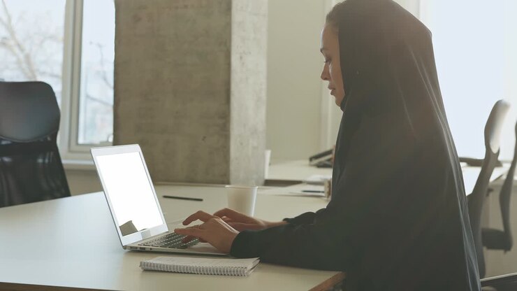 Schöne arabische Frau im Abaya-Kleid arbeitet im Büro