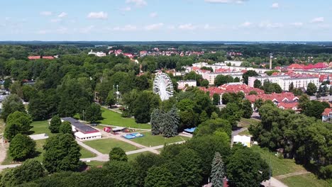 cozy town of gizycko with ferris wheel surrounded by green forest, aerial view