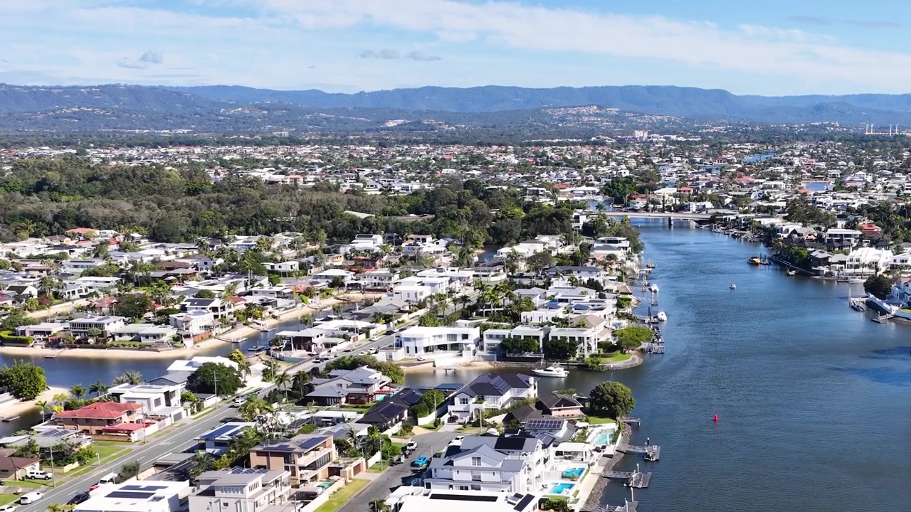 Imágenes de dron capturan casas residenciales de lujo bordeando un serpenteante curso de agua azul bajo cielos despejados.